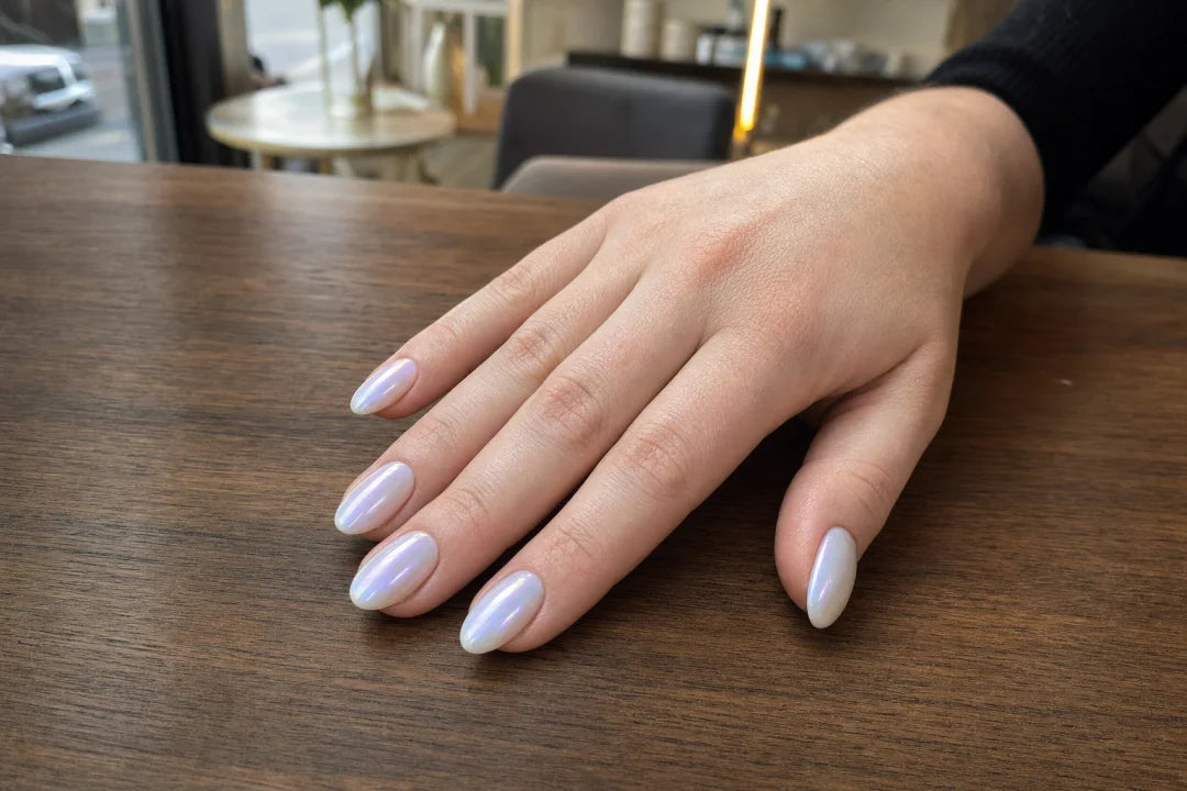 Perłowy manicure na średnich migdałkach z mlecznobiałą bazą i opalizującym chłodnym poblaskiem w świetle dziennym